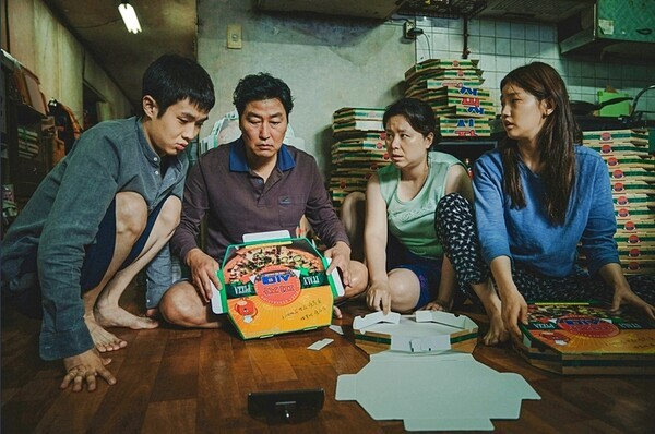 영화 '기생충'에서 반지하층에 사는 가족이 피자 상자를 접고 있다(출처=씨네21)